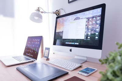 棕色木桌上iPhone附近的银色iMac